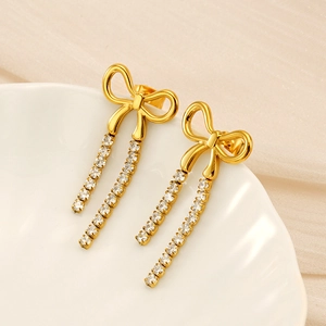 Detailed macro view of golden bow earrings with sparkling rhinestone tassels on ceramic