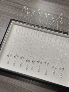 Macro shot of 925 silver necklaces featuring blue teardrop pendants on wood background