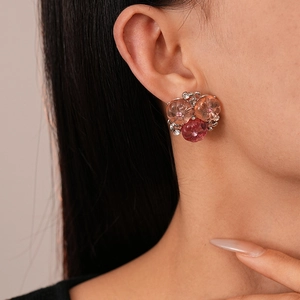 Floral resin earrings with gradient pink crystal beads worn by model in a side view profile