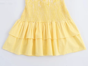 Detail of yellow gingham dress featuring elastic smocked waist and tiered ruffle hemline