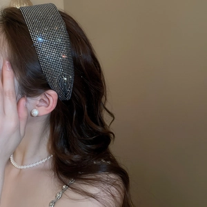 Close-up of wide sparkling rhinestone headband with shiny crystals on brown hair