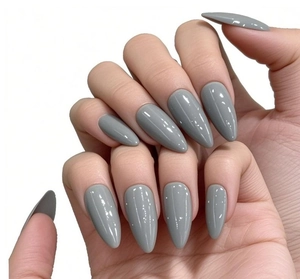 Faux ongles stiletto gris brillants posés sur mains sur fond blanc minimaliste épuré