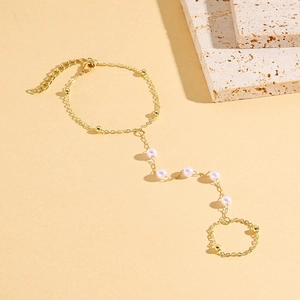 Detail of gold finger bracelet with pink pearls and lobster clasp on stone decor