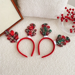 Detail of red and green plaid Christmas reindeer antler headbands on plush background