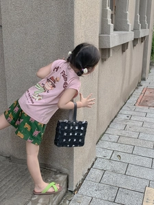 Detailed view of child's black woven bucket bag with elegant hollow texture