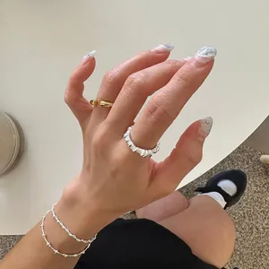 Close-up of minimalist silver irregular textured ring and golden band on model's hand