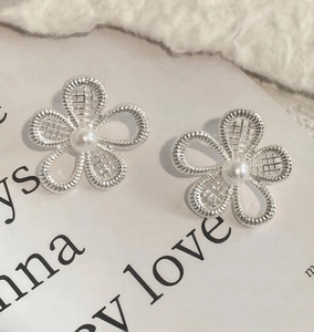 Macro view of silver flower earrings with intricate hollow petals and center pearl