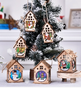 Detailed view of six lighted wooden Christmas house ornaments hanging on a festive tree