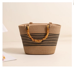 Detail of hand-woven straw bag with black stripes and natural bamboo handle accents