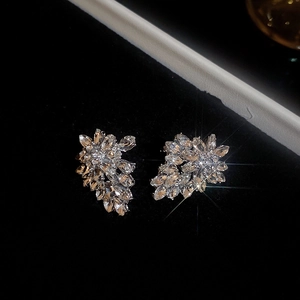Detailed view of silver leaf stud earrings with sparkling diamonds on dark velvet