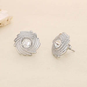 Detail of silver spiral stud earrings with sparkling round zircon on beige background