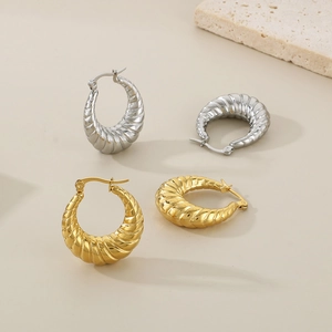 Macro view of gold and silver croissant twist earrings with textured spiral hoop design