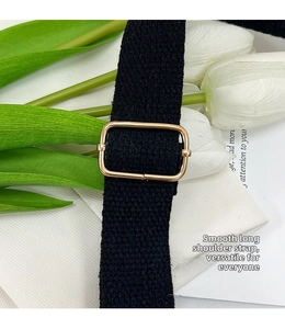 Detail of adjustable black woven shoulder strap with premium gold metal buckle
