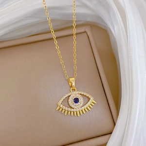 Macro shot of gold Evil Eye necklace with blue gemstone and diamonds on silk