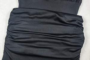 Detailed view of black ruched fabric with satin sheen on a slim fit dress for women