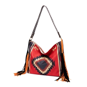 Close-up of bohemian woven shoulder bag featuring geometric patterns and orange tassels