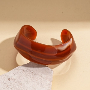 Macro detail of dark red acrylic bangle with marble texture on natural stone base
