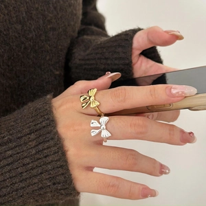 Close-up of minimalist S925 silver bow rings in gold and silver finishes on a model