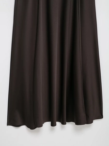 Detailed close-up of the smooth black satin dress hem with elegant draping folds