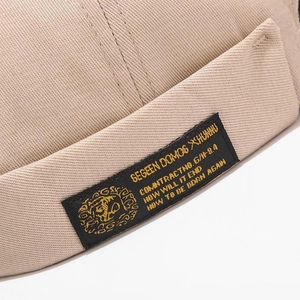 Close-up of the beige cotton docker hat showing the twill texture and logo label detail