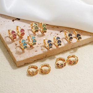 Golden heart earrings with colorful zircon stones on marble and silk background