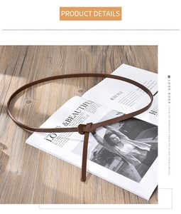 Close-up of minimalist dark brown slim waist belt tied in a knot on a wooden surface