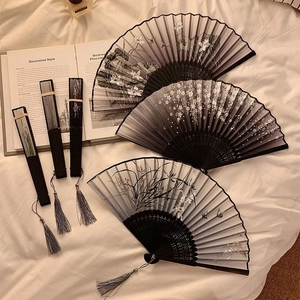 Traditional Chinese folding fans with ink painting patterns and silk tassels on white fabric