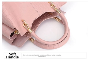 Detail of pink faux leather handbag showing crocodile texture and gold metal handle buckles