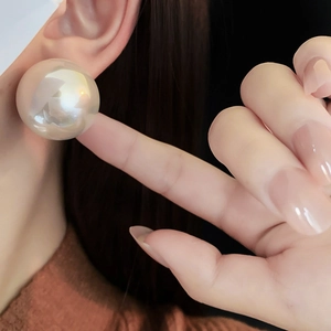 Close-up of extra large pearl stud earring with iridescent sheen on female model