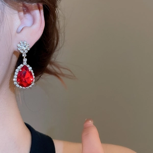 Detailed side view of silver teardrop earrings with a vibrant red gemstone and micro-pave diamonds