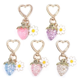 Set of five resin strawberry keychains with glitter and daisies on white background