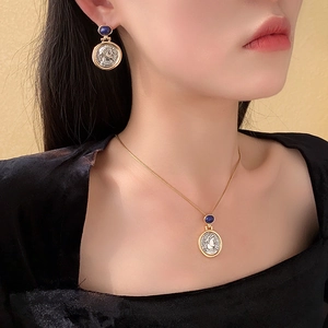 Detail of French vintage coin pendant earrings and necklace with blue gemstones