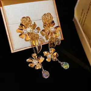 Elegant gold flower tassel earrings with pearls and crystals on a black velvet display