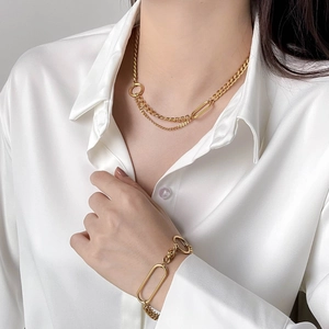 Gold chunky chain necklace and bracelet set with geometric rings on a white shirt