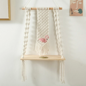 Detail of bohemian hand-woven macrame wall shelf with cotton rope and wooden board