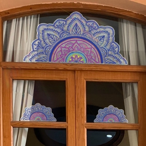 Rainbow mandala window decals showing holographic patterns on a brown wooden glass window