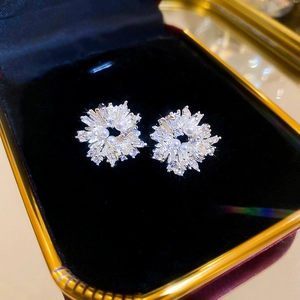 Gros plan de boucles d'oreilles fleurs avec zircon et perles sur un plateau en velours