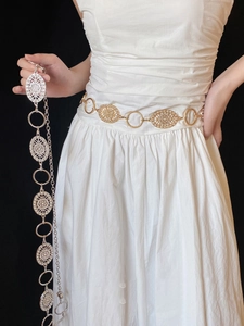 Detailed view of vintage gold and silver metal chain belts with hollow carved flowers