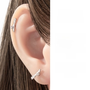 Macro shot of silver star zircon dagger earring worn on ear showing design concept details