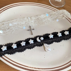 Détail du ras-du-cou en dentelle blanche et collier en velours noir avec perle goutte