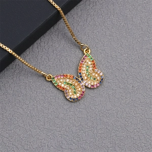 Macro shot of a golden butterfly necklace with colorful cubic zirconia on a gray surface