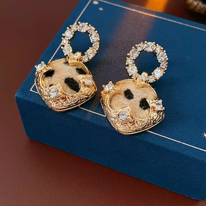 Macro shot of gold leopard print earrings with white rhinestones on a blue jewelry box