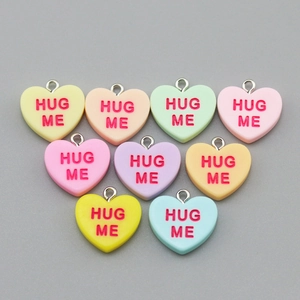 Macro shot of colorful resin heart pendants with Hug Me text and silver metal loops