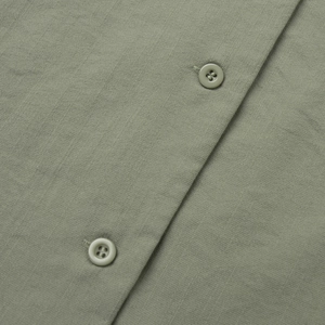 Macro shot of bean green cotton-linen shirt buttons and fine fabric texture details
