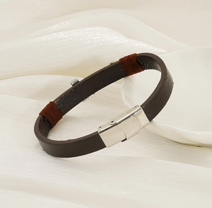 Détail d'un bracelet en cuir marron foncé avec fermoir argenté et décorations tissées