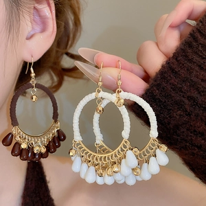 Detail of bohemian cotton rope wrapped earrings with droplet beads and gold metal accents