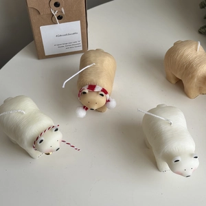 Macro shot of polar bear scented candles with festive scarves and bells on a white desk