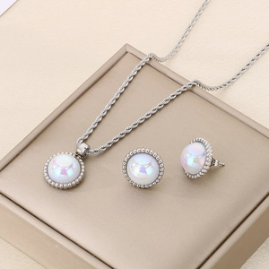 Detail of twisted chain necklace and pearl earrings set on a beige jewelry box
