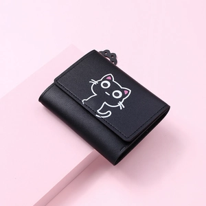 Close-up of black trifold cat wallet with cute paw charm on a pink background