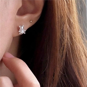Macro shot of silver teddy bear stud earrings with pearl inlay worn on ear